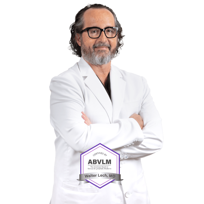 VTC_DrLech_CutOut-w-bagde_800x800 Professional portrait of Dr. Walter Lech, a healthcare provider specializing in vein treatment, wearing a white clinical coat over a black shirt and eyeglasses. The formal headshot is taken against a black background, typical of medical practice promotional photography for a vein treatment specialist.